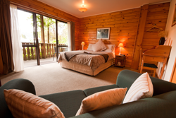 Interior view of hotel room with large couch, bed and porch with sliding doors