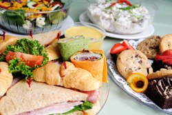 Sandwhiches, salads, and desserts sitting on table