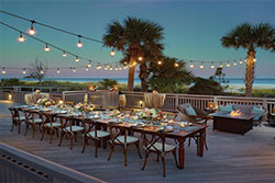 Ocean Deck with patio lights, decorated table and palm trees in background